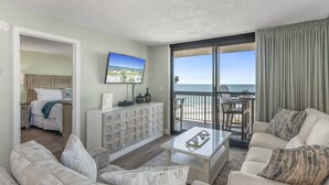 A modern hotel room with a balcony, a bed, a seating area, and a TV on the wall. - SunDestin 1518*Remodeled*Panoramic Views*Hot Tubs*Pool*Restaurant (Destin)