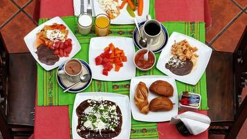 A table with a variety of dishes, including tacos, a plate of enchiladas, and a bowl of soup.