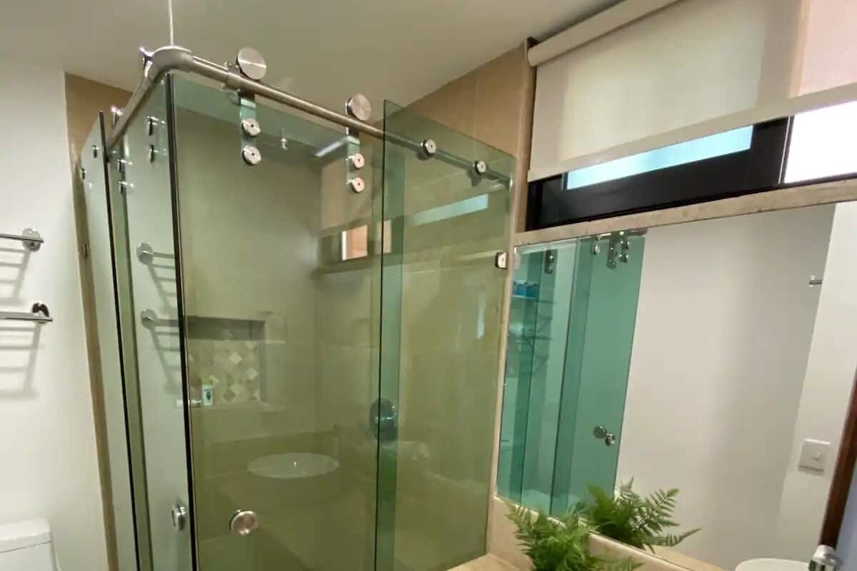 A modern bathroom with a glass-enclosed shower, a sink with a mirror, and a toilet.