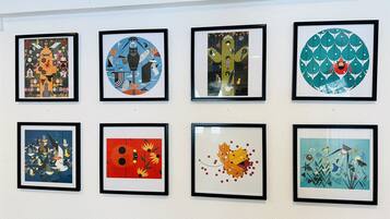 Acht gerahmte Kunstwerke an einer Wand.