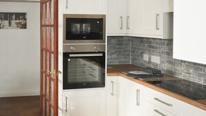 A kitchen with white cabinets, a double oven, a microwave, and a black tiled backsplash. - 4 bedroom accommodation in Whitby (Whitby)