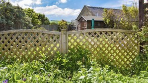 A wooden lattice fence with a garden in the foreground and a house with a sloped roof in the background. - 4 bedroom accommodation in Whitby (Whitby)
