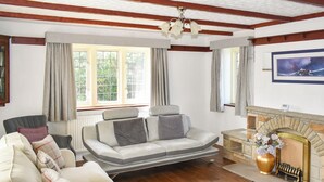 A living room with a sofa, armchairs, a fireplace, and a painting on the wall. - 4 bedroom accommodation in Whitby (Whitby)