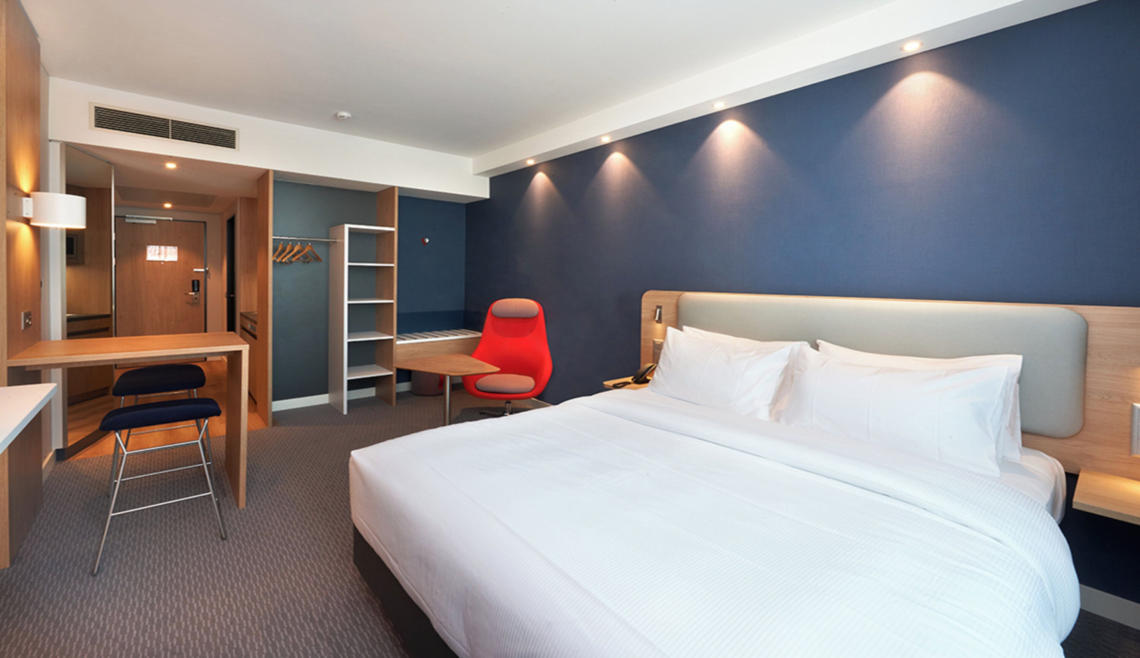 Una habitación de hotel con una cama grande, un escritorio, una silla y un armario.