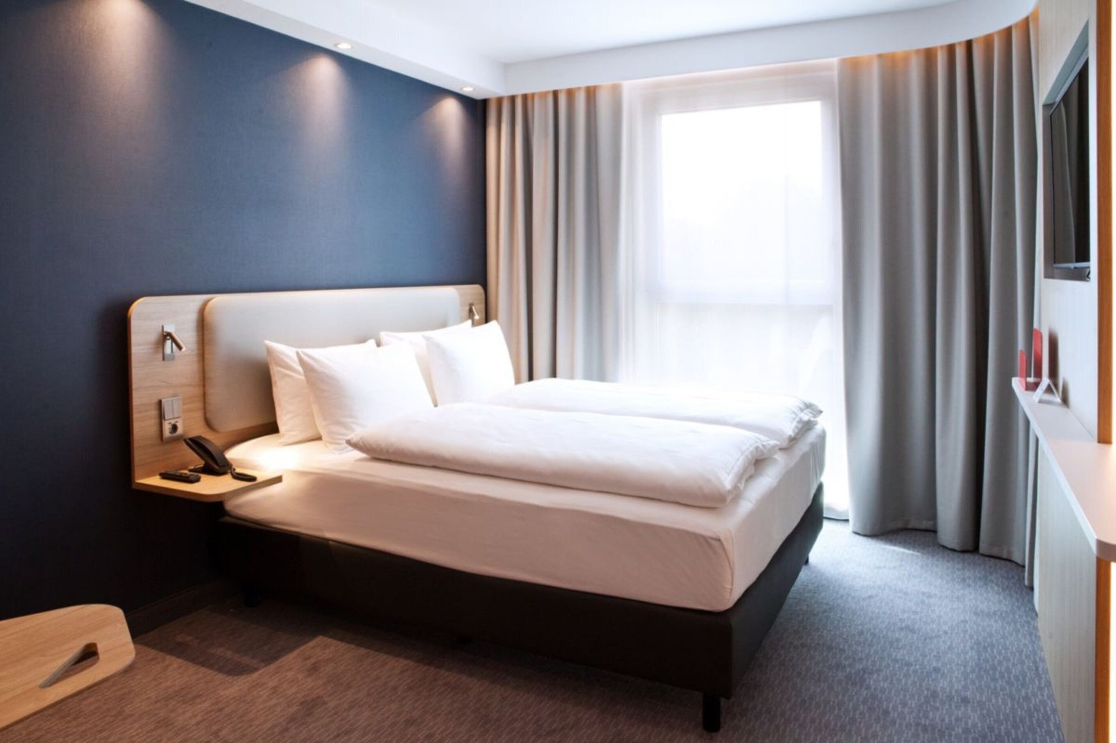 Ein Hotelzimmer mit einem Bett, einem Nachttisch und einem Telefon.