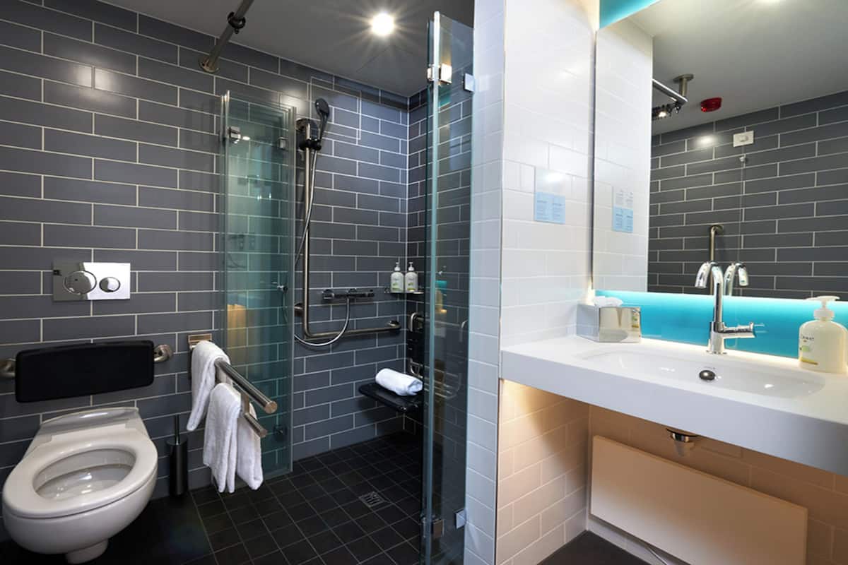 Un baño moderno con inodoro, cabina de ducha con mampara de vidrio y lavamanos con espejo.
