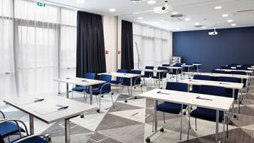 A conference room with tables, chairs, and a projector.