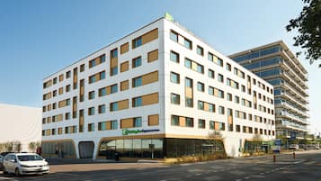 Situated on a street corner, this hotel offers a modern, symmetrical design with rectangular windows and a flat roof.