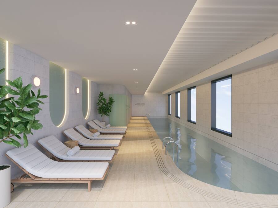 Un área de piscina interior moderna con sillones de descanso y plantas en macetas.