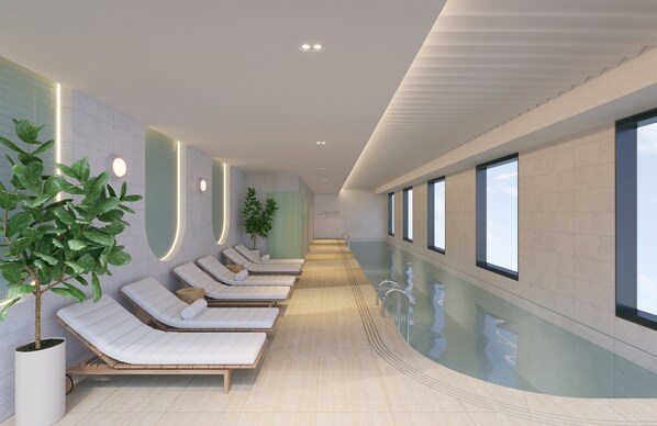 A modern indoor pool area with lounge chairs and potted plants.