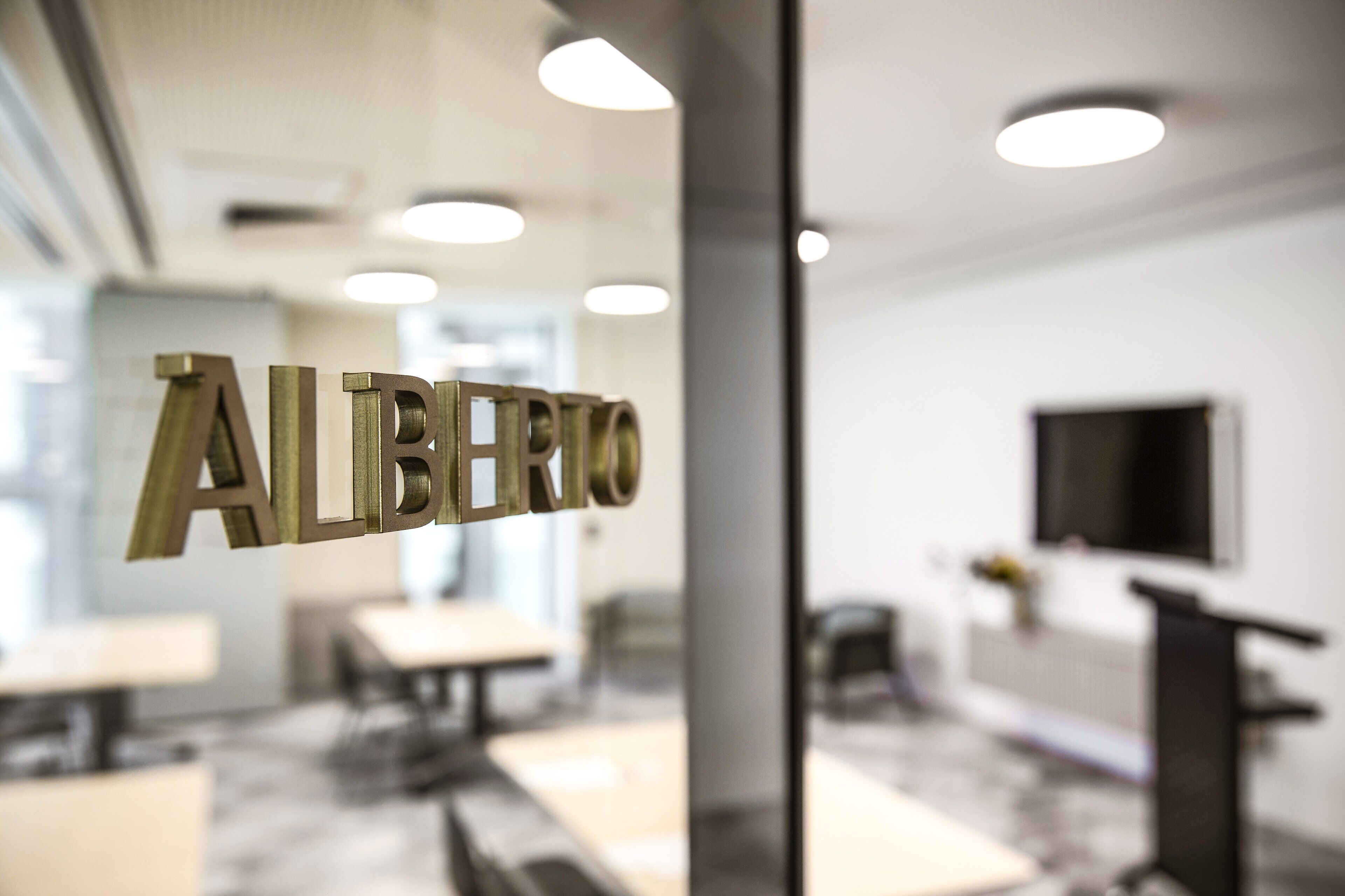 A modern interior with a glass partition displaying the word "ALIBERTO".