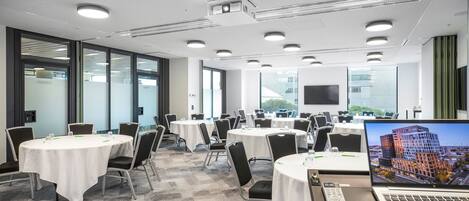A conference room with multiple tables, chairs, and a laptop displaying a cityscape.