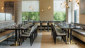 A modern restaurant with a long communal table, cushioned seating, and pendant lighting. - Holiday Inn & Suites Geelong by IHG (Geelong)