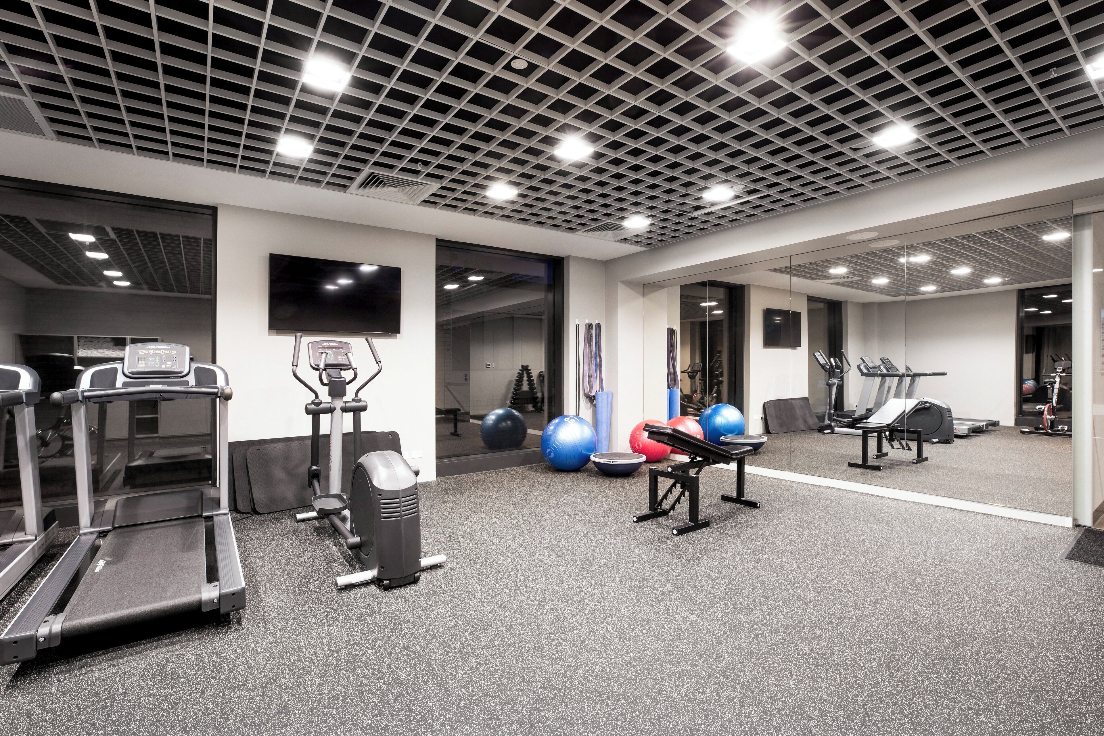 A gym with treadmills, elliptical machines, and exercise balls.