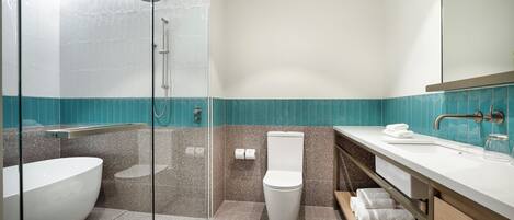 Un baño moderno con ducha envuelta en vidrio, una bañera independiente y un tocador con espejo.