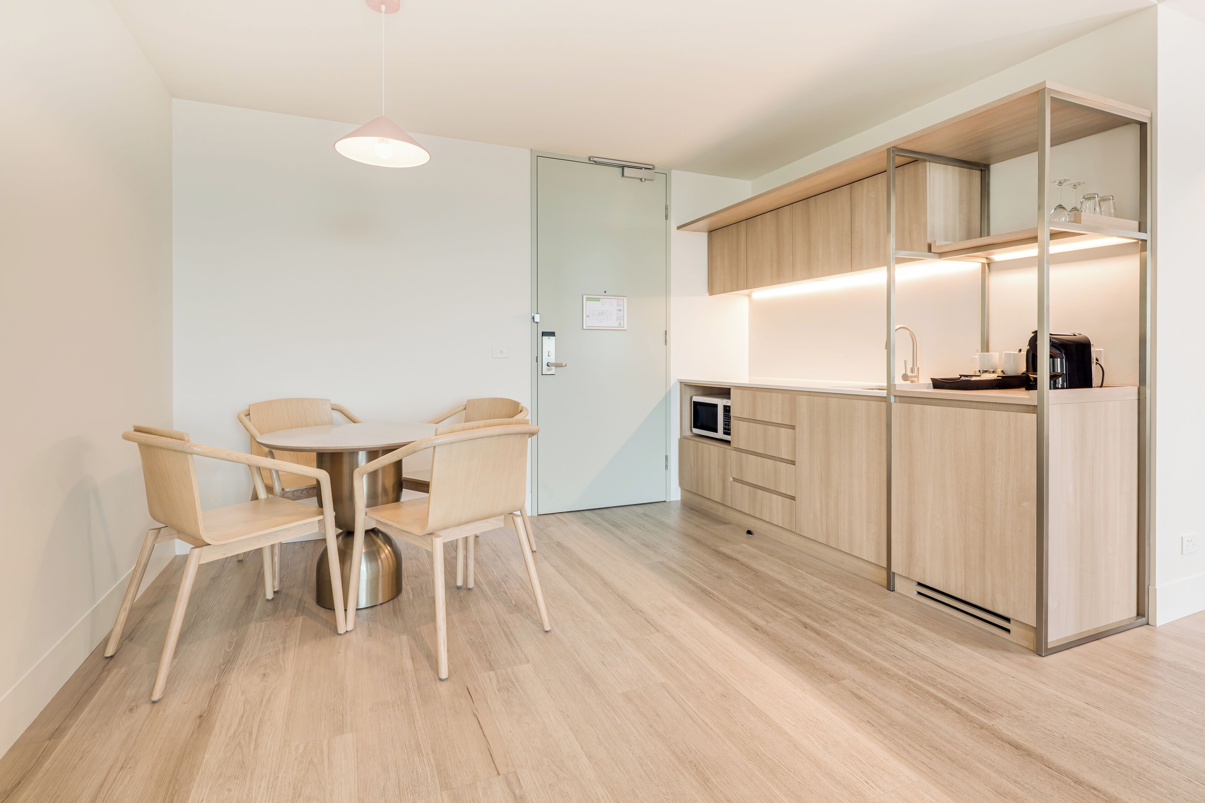 Una cocina moderna con armarios de madera, una zona de comedor con una mesa redonda y sillas, y un microondas.