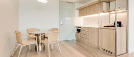 Una cocina moderna con armarios de madera, una zona de comedor con una mesa redonda y sillas, y un microondas.