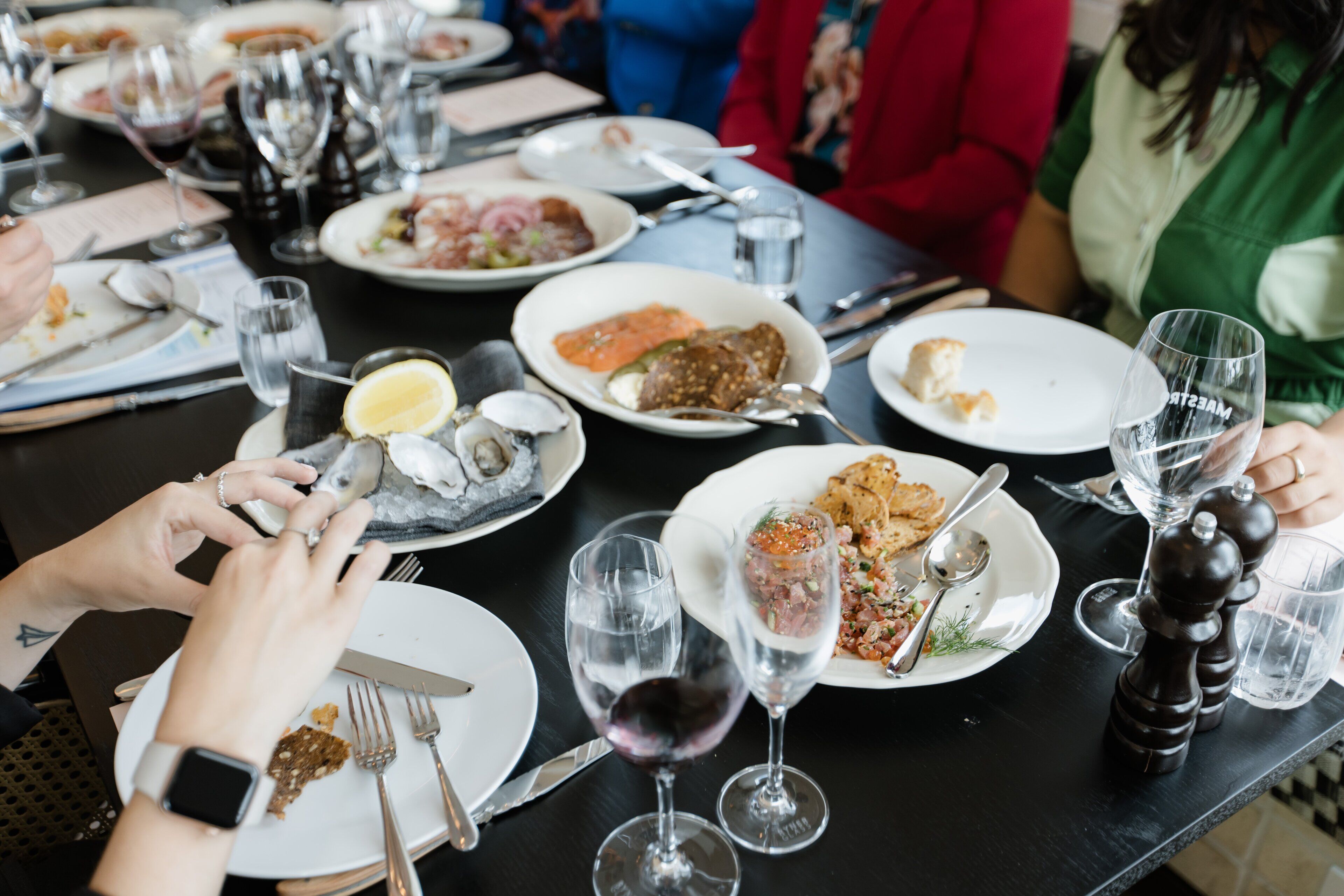 A dining table with various dishes, wine glasses, and cutlery.