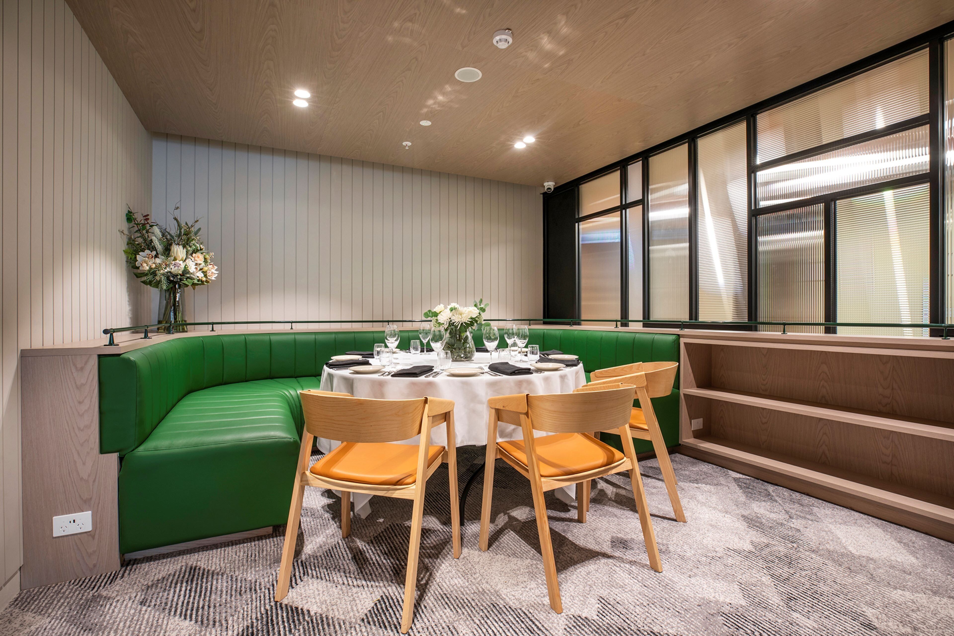 A dining area with a green cushioned bench, round tables, and wooden chairs.