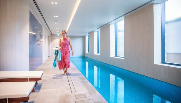 A poolside area with a tiled floor, benches, and a clear blue pool. - Holiday Inn & Suites Geelong by IHG (Geelong)