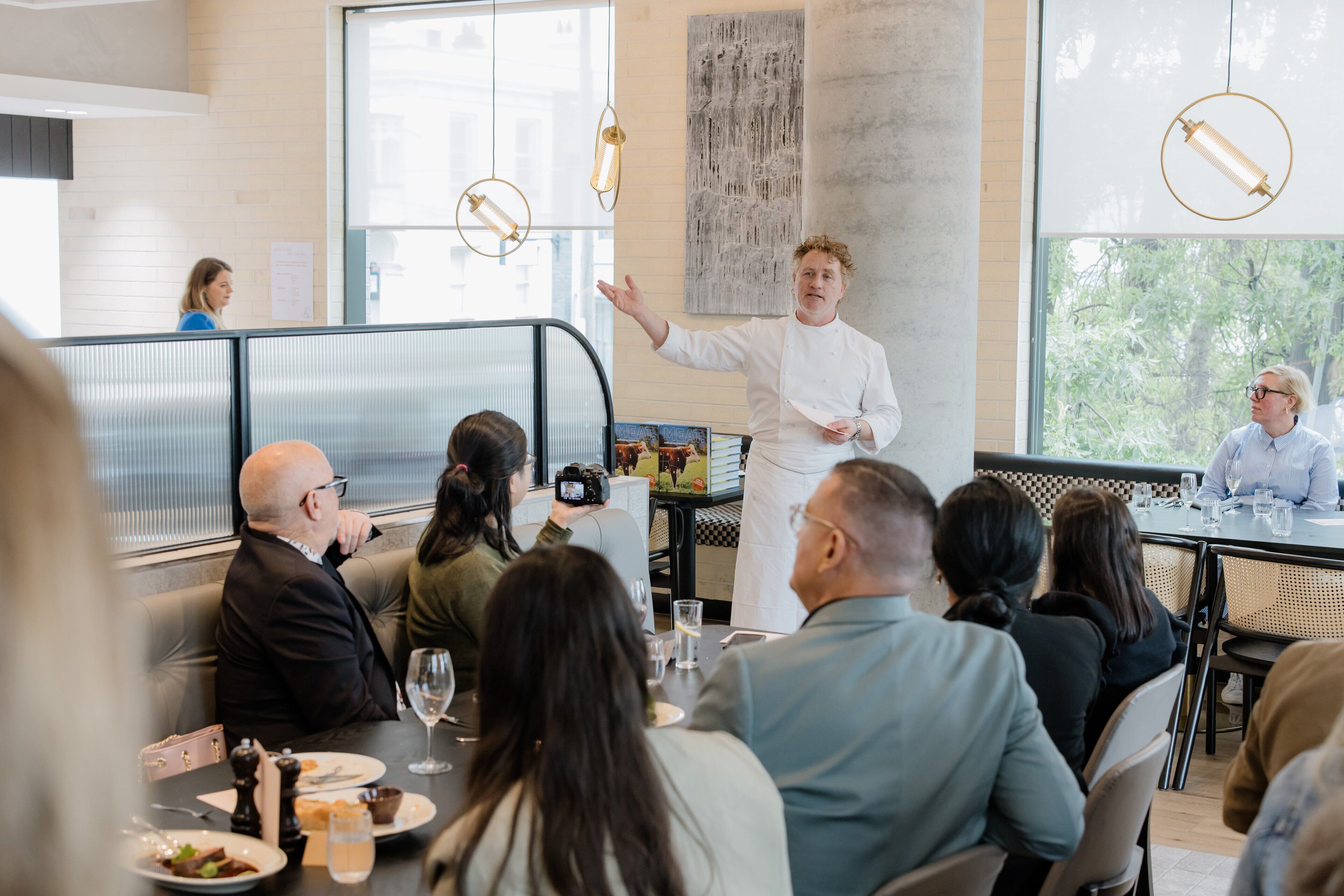 A modern dining area with a chef presenting to a group of diners.