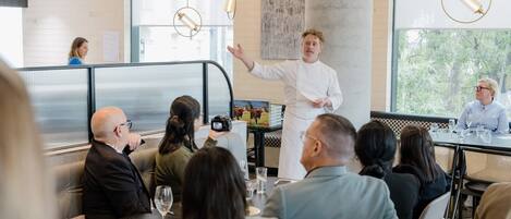 A modern dining area with a chef presenting to a group of diners.