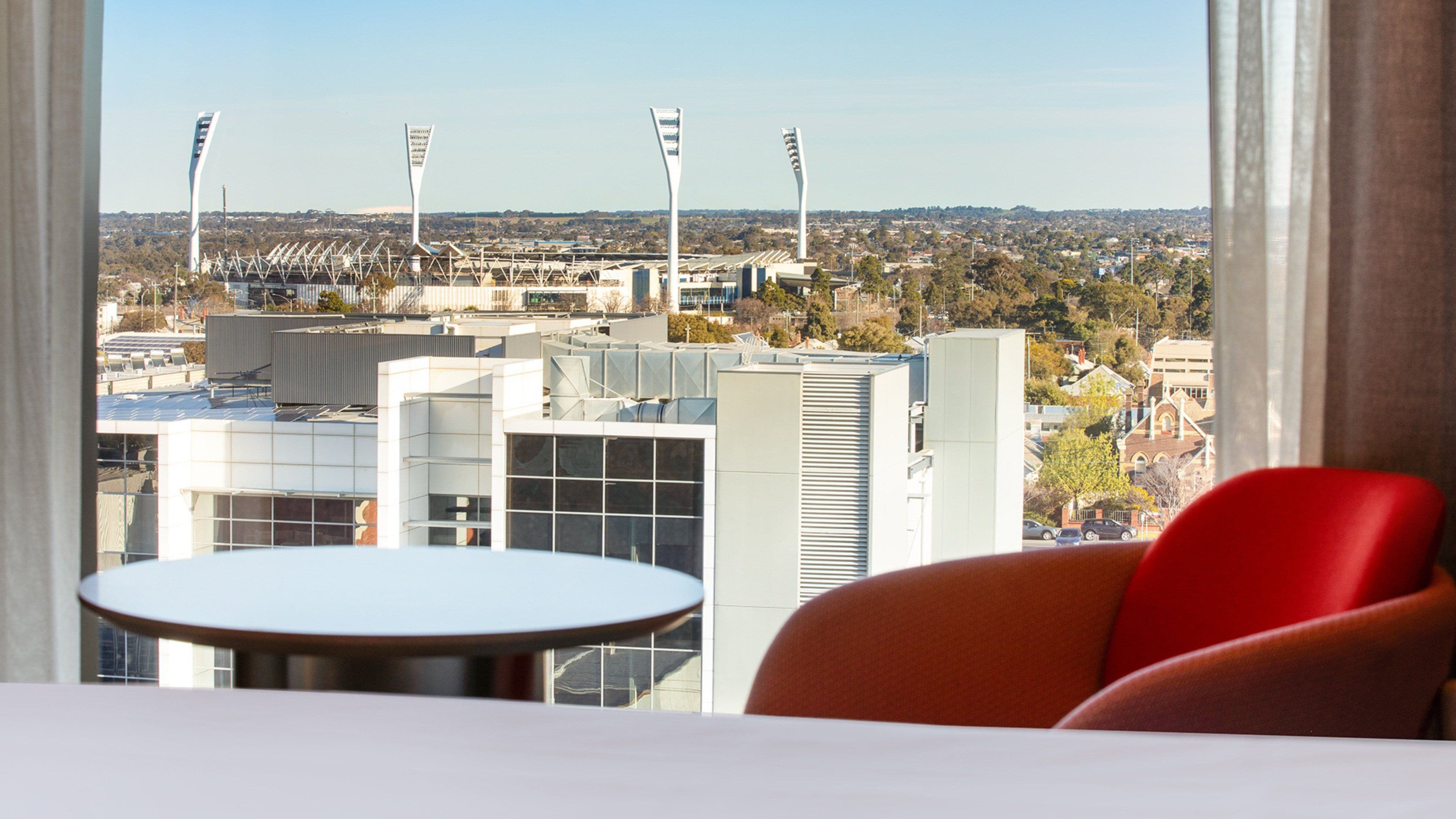 Habitación de hotel con vista a un estadio y edificios circundantes.
