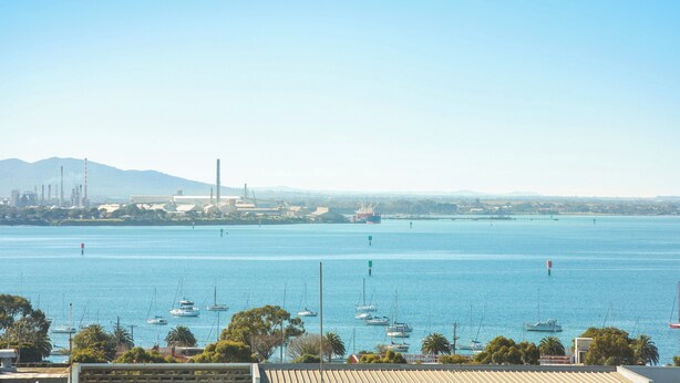 A marina with boats and a distant industrial area.