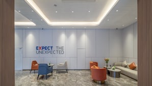 Un área de recepción moderna con un lema en la pared, un sofá, sillas y una mesa de centro.