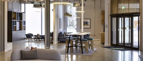 Un intérieur moderne avec un canapé incurvé, un coin repas et un comptoir d’accueil.