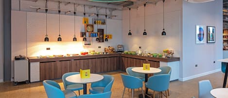 A modern kitchen with a central island, blue chairs, and pendant lighting.