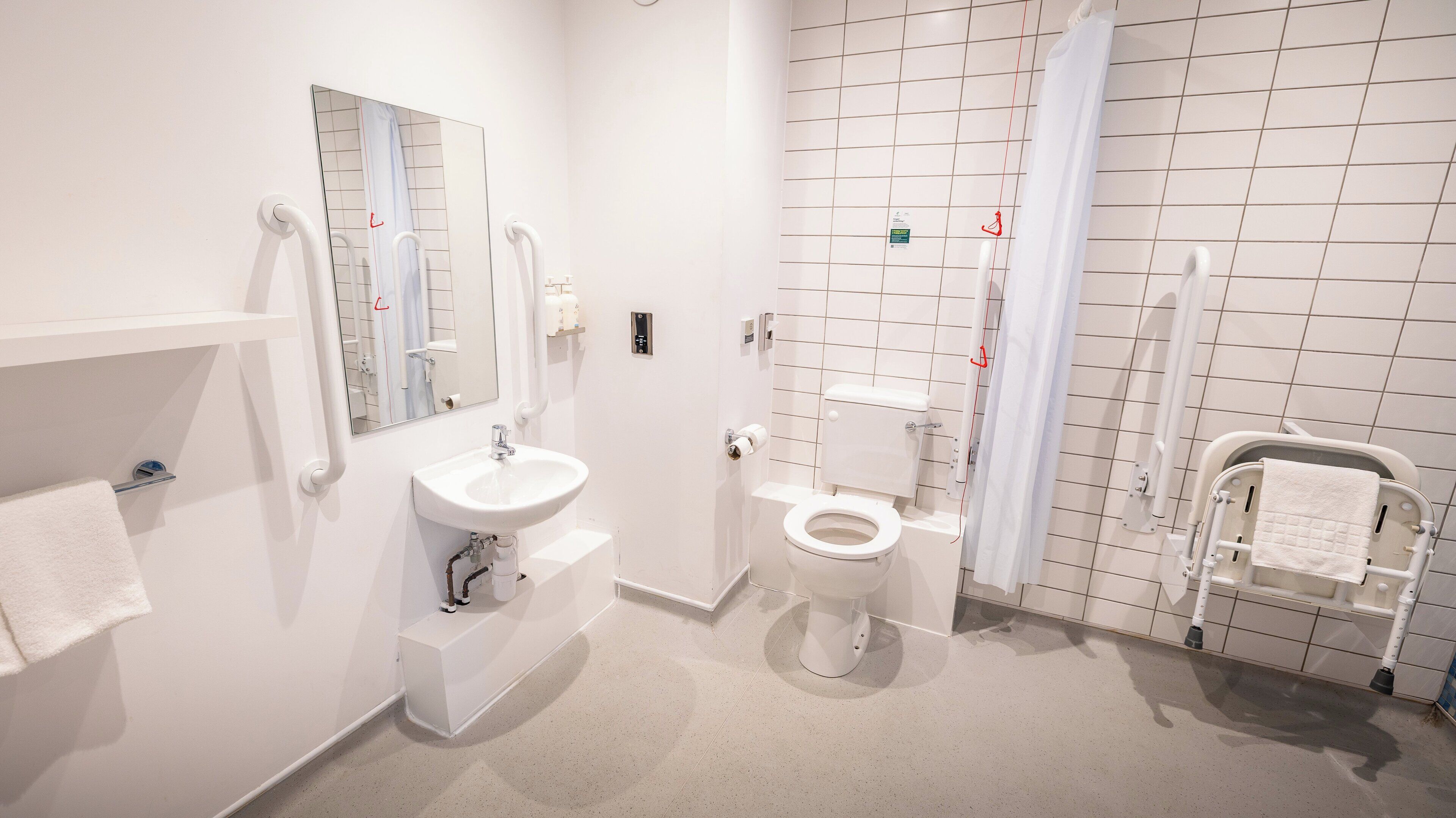 A modern bathroom with a white sink, toilet, and shower area.