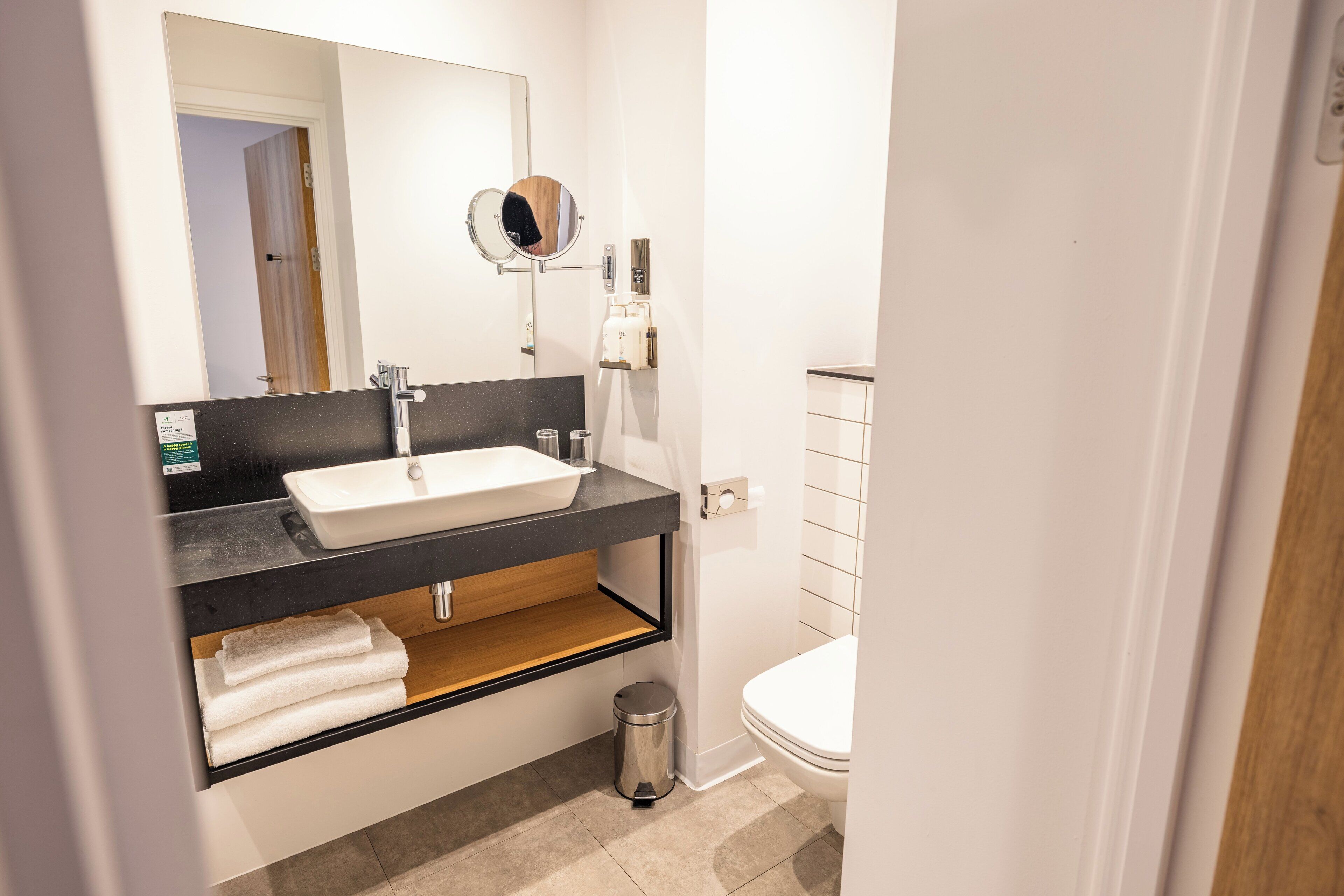 A modern bathroom with a white sink, black countertop, and a mirror above it.