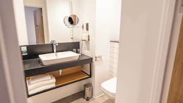A modern bathroom with a white sink, black countertop, and a mirror above it.