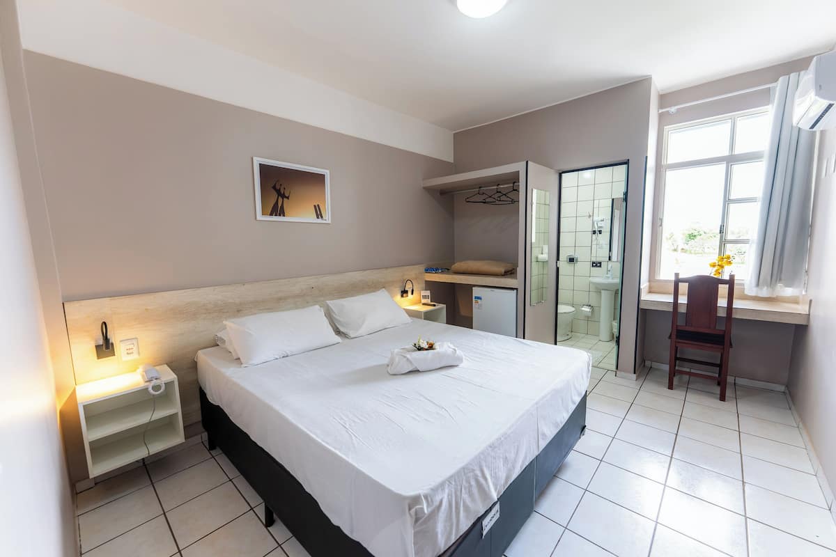 Une chambre d’hôtel comprenant un lit, une table de chevet, un bureau, une chaise et un espace douche.