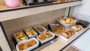 Noutopöytä, jossa on tarjolla monenlaisia ruokia, kuten leipää, leivonnaisia ja salaattia.