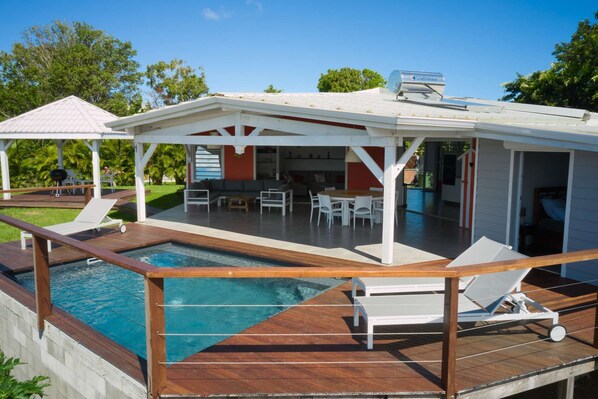A poolside area with a covered seating area, a pool, and a view of the backyard. - Full equiped Villa with swimming pool (Deshaies)