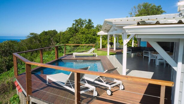 A pool area with lounge chairs and a covered seating area overlooking a scenic view. - Full equiped Villa with swimming pool (Deshaies)