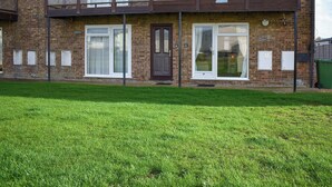 Ein zweistöckiges Ziegelhaus mit Balkon, Hausnummer 21, und einem gepflegten Vorgarten.