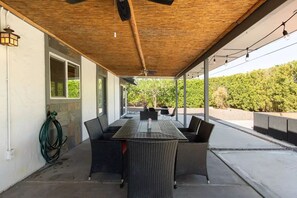 Enjoy dining al fresco in this covered patio area with a long dining table and comfortable seating.