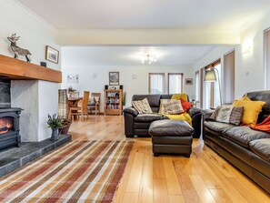A living room with a fireplace, leather sofas, a striped rug, and a dining area with wooden furniture.