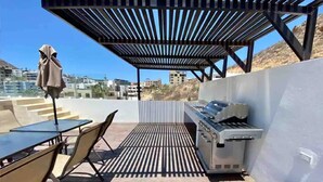 Un patio al aire libre con una parrilla, mesas y sillas.