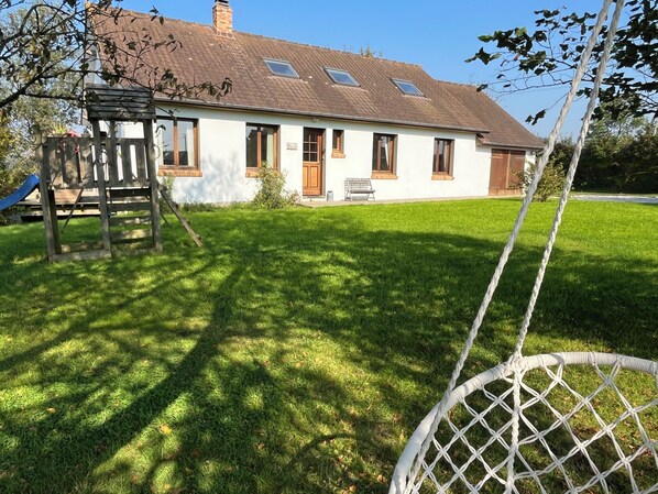 A house with a sloped roof, a wooden deck, and a well-maintained lawn.