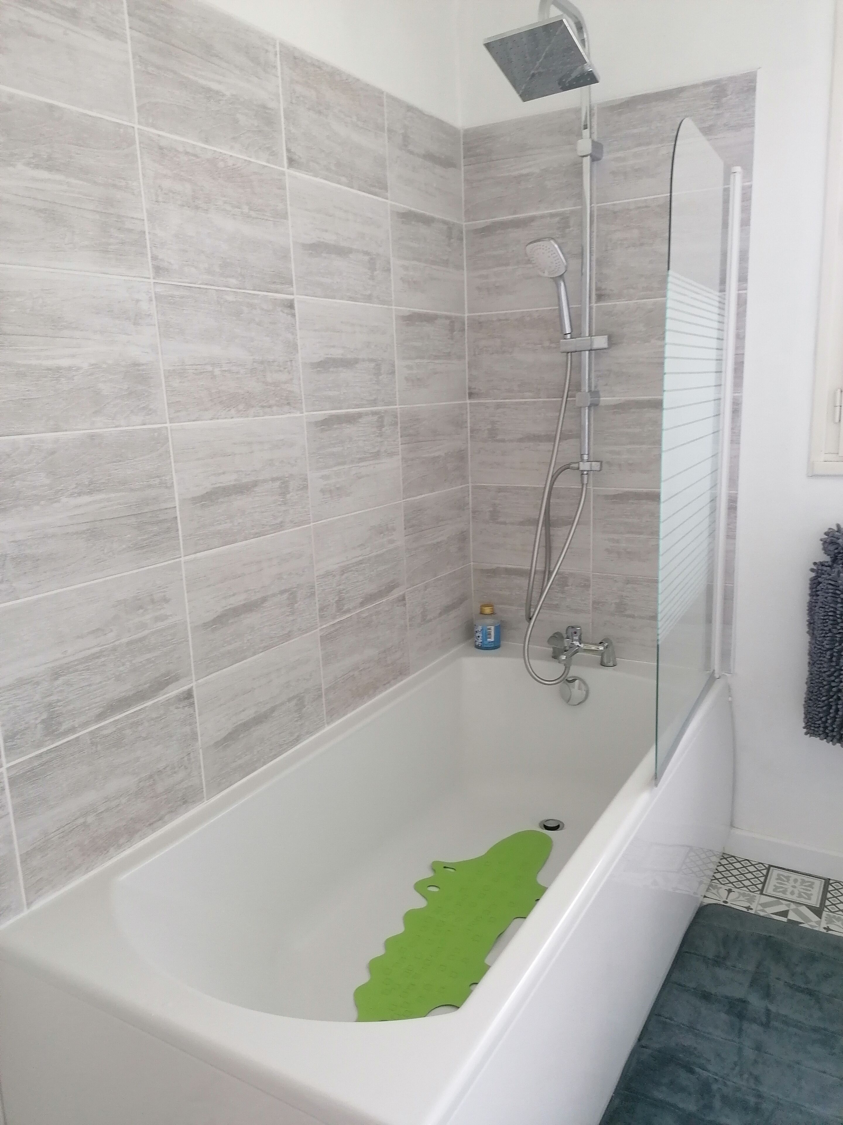 A bathroom with a bathtub, shower, and tiled walls.