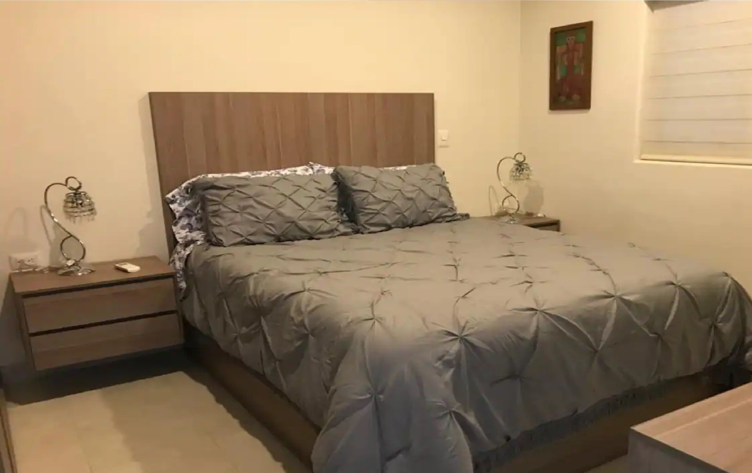 A bedroom with a bed, nightstands, and a painting on the wall.