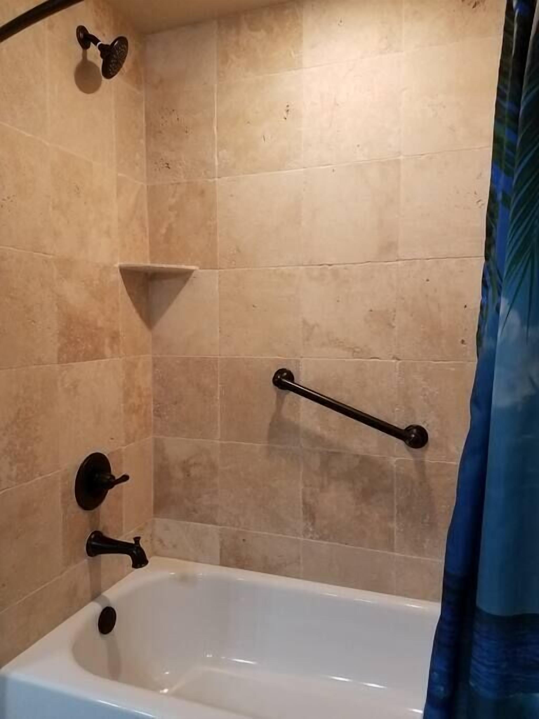 A bathroom with a bathtub, a shower, and a handrail.