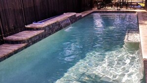 Ein rechteckiger Pool mit Steinbord und einem kleinen Wasserfall.