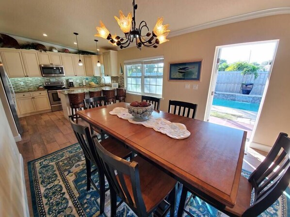 A spacious kitchen with a wooden dining table, chairs, and a chandelier.