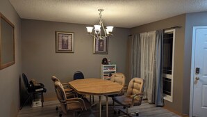 A dining room with a round table, six chairs, a chandelier, framed artwork on the walls, and a bookshelf. - 6 beds entire house fenced Yard,  2 car Pad + Garage (3 beds at basement) (Calgary)