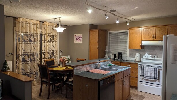A compact kitchen with wooden cabinets, a built-in dishwasher, and a refrigerator. - 6 beds entire house fenced Yard,  2 car Pad + Garage (3 beds at basement) (Calgary)